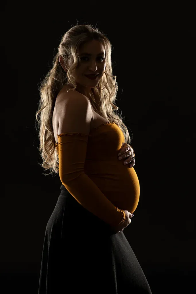 Natürliches Babybauch Portrait in Zofingen mit warmem Outfit, dunklem Hintergrund und ruhiger Lichtstimmung