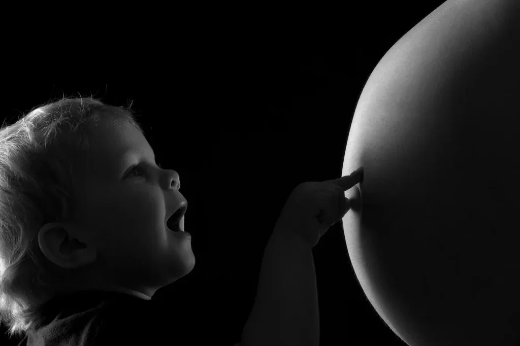Emotionales Babybauch Shooting mit Geschwisterkind, zarter Berührung und ruhiger Schwarzweiss-Bildsprache