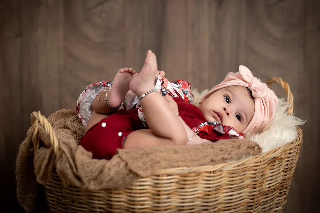 Natürliches Babyfoto in Zofingen mit Baby im Korb, rosa Stirnband und warmer Studioatmosphäre