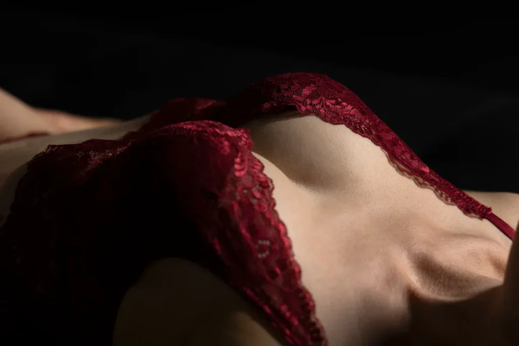Sinnliche Detailaufnahme mit roter Spitze, weichem Licht und stilvoller Boudoir-Atmosphäre