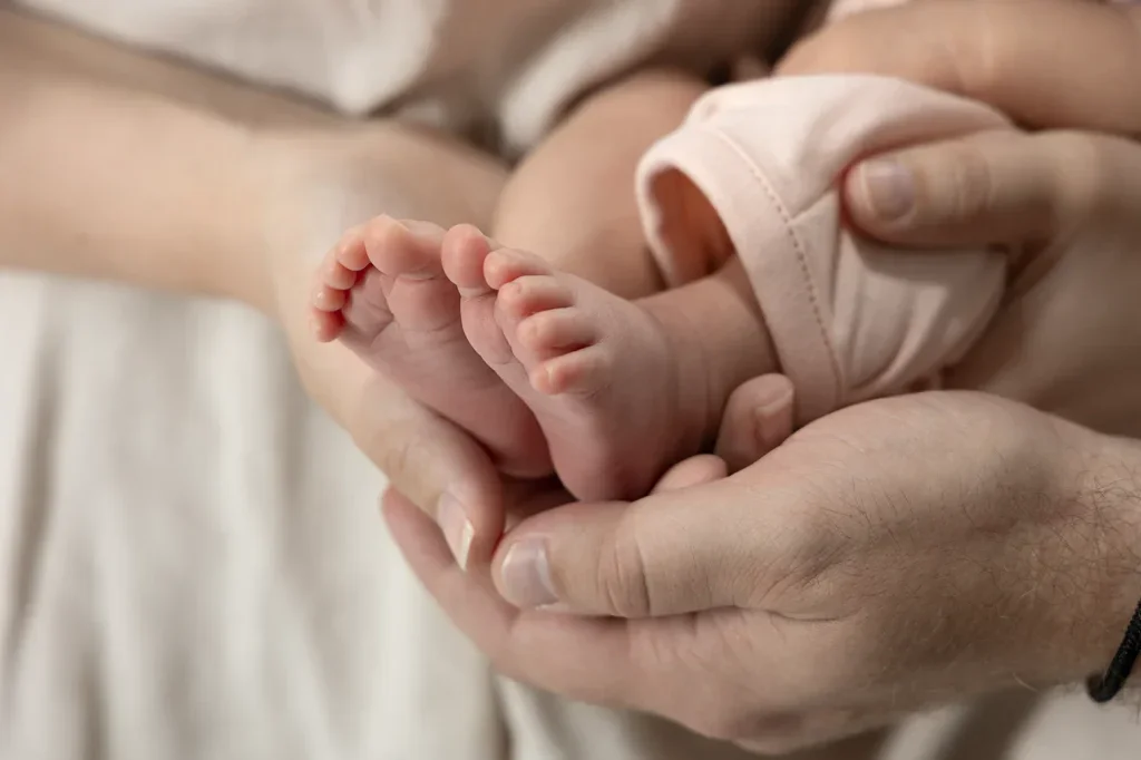 Liebevolle Detailaufnahme kleiner Babyfüsse in den Händen der Eltern bei einem natürlichen Newborn Shooting