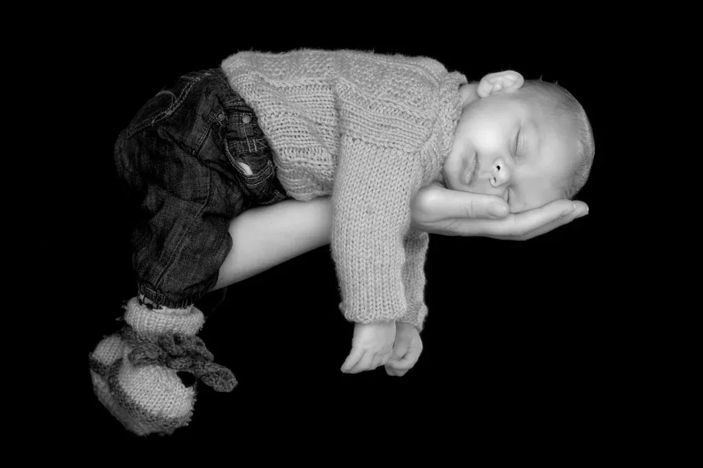 Schwarzweisses Newborn Foto mit schlafendem Baby auf der Hand, ruhiger Lichtstimmung und liebevollem Detail