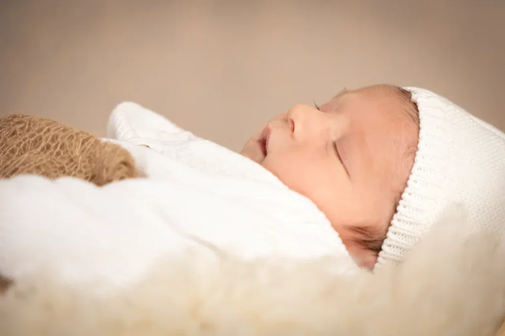 Liebevolles Newborn Portrait in Zofingen mit schlafendem Baby, weisser Mütze und weichem Licht