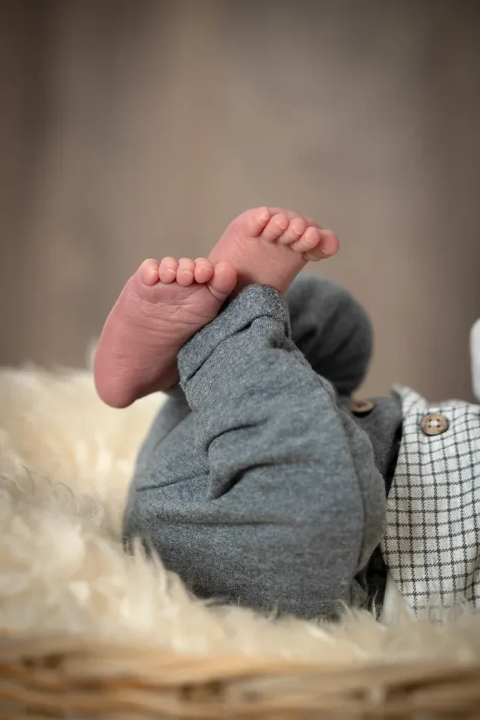 Liebevolle Detailaufnahme kleiner Babyfüsse bei einem natürlichen Newborn Shooting im Fotostudio