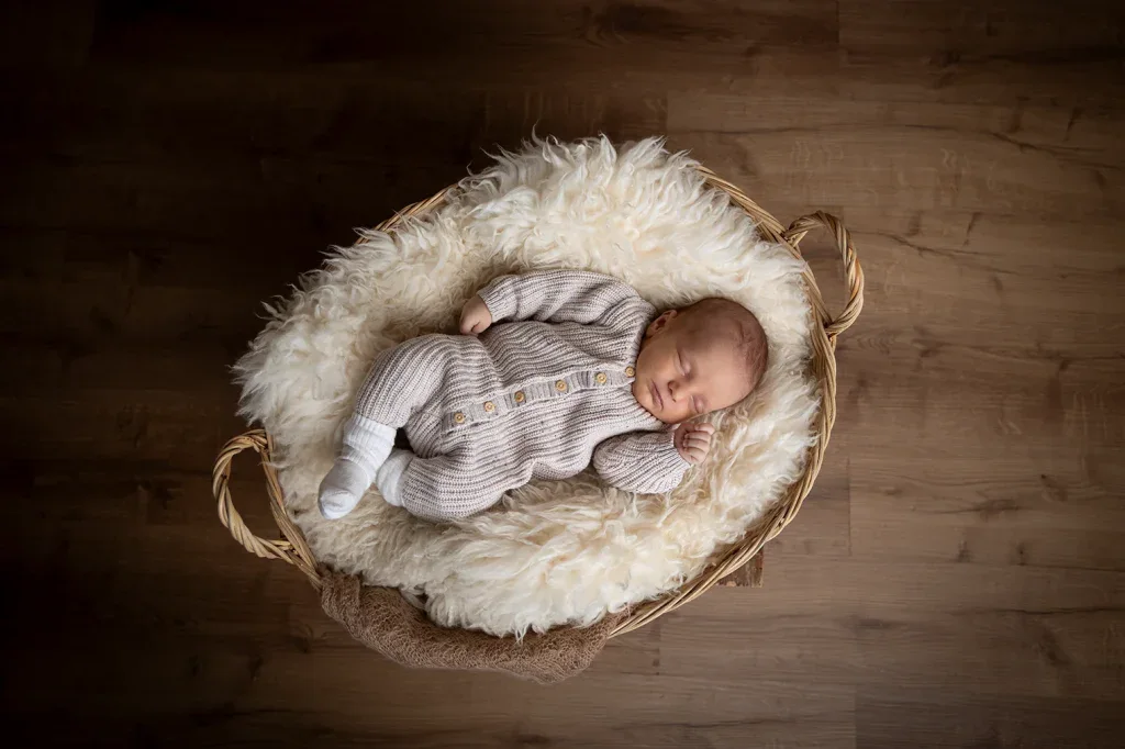 Natürliches Newborn Shooting in Zofingen mit schlafendem Baby im Korb, weicher Decke und warmer Bildstimmung