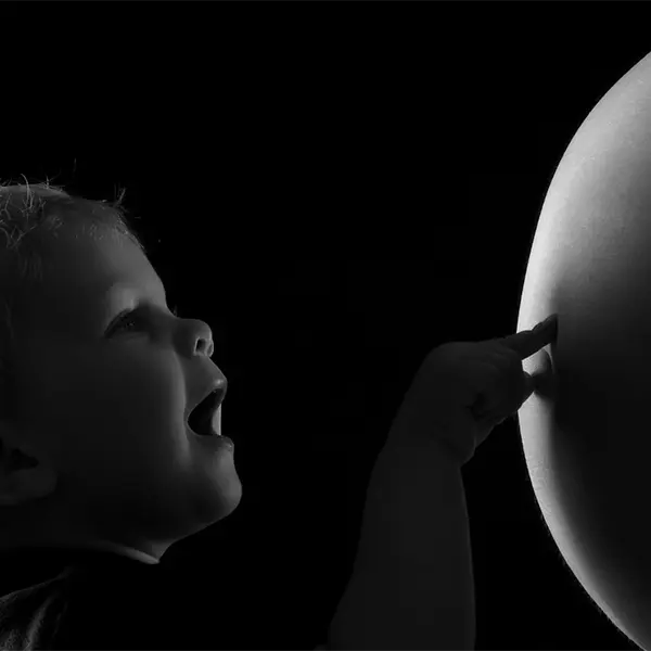 Emotionales Babybauch Shooting in Schwarzweiss mit Geschwisterkind, zarter Berührung und ruhiger Lichtstimmung