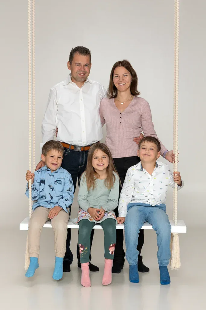 Natürliches Familienfoto in Zofingen mit Eltern und drei Kindern auf Schaukel im Fotostudio Fokus