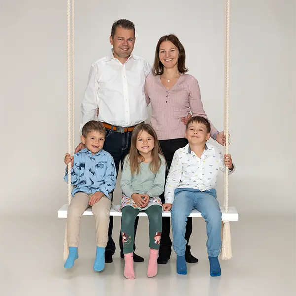 Familie mit drei Kindern auf einer Schaukel beim Familienfotoshooting im Studio