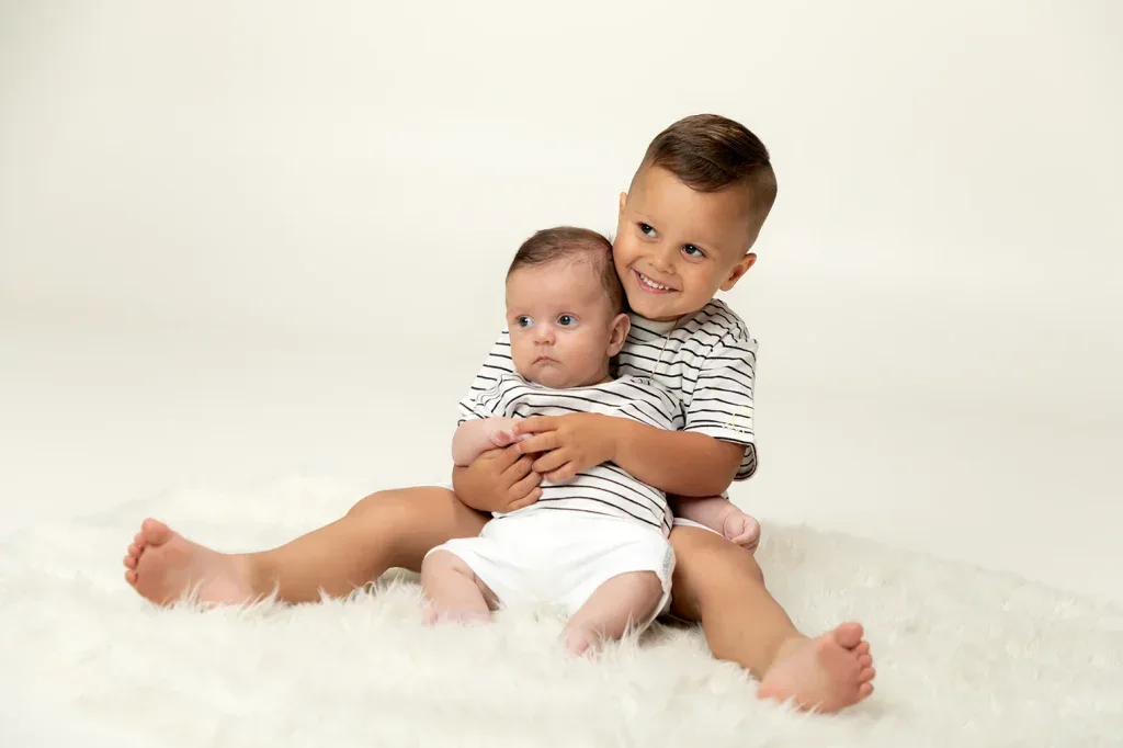 Liebevolles Geschwisterfoto in Zofingen mit grossem Bruder und Baby auf weichem Fell