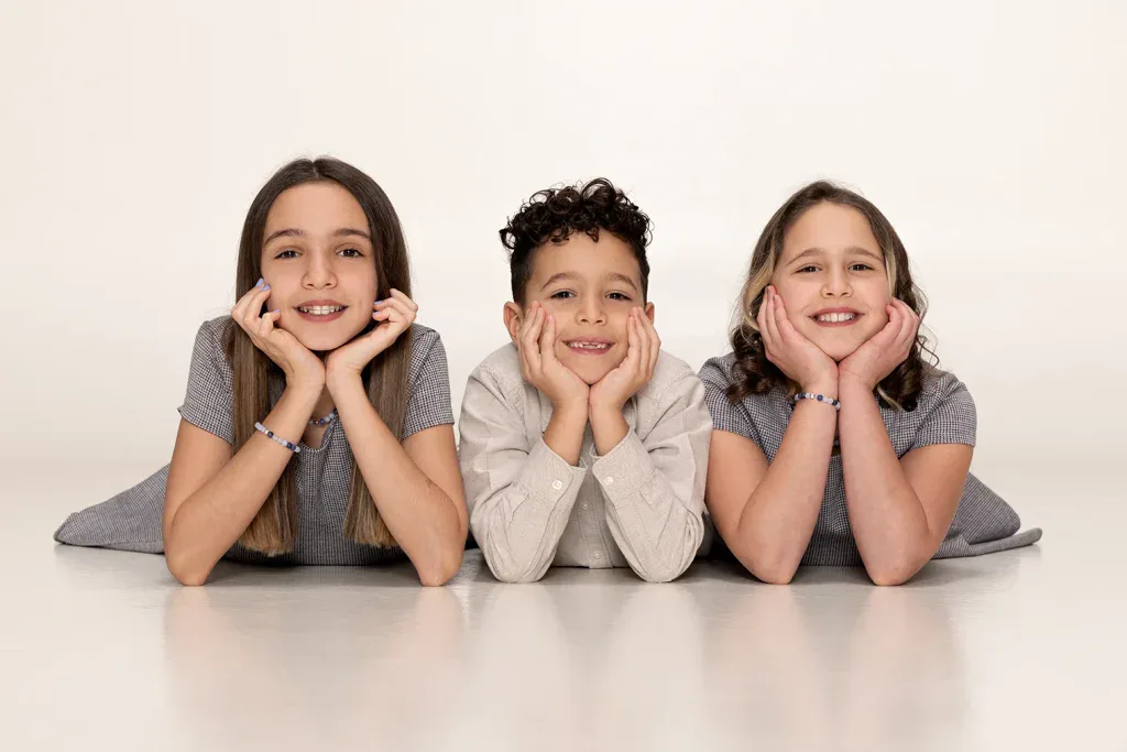 Natürliches Geschwisterfoto in Zofingen mit drei lachenden Kindern, hell fotografiert im Fotostudio Fokus