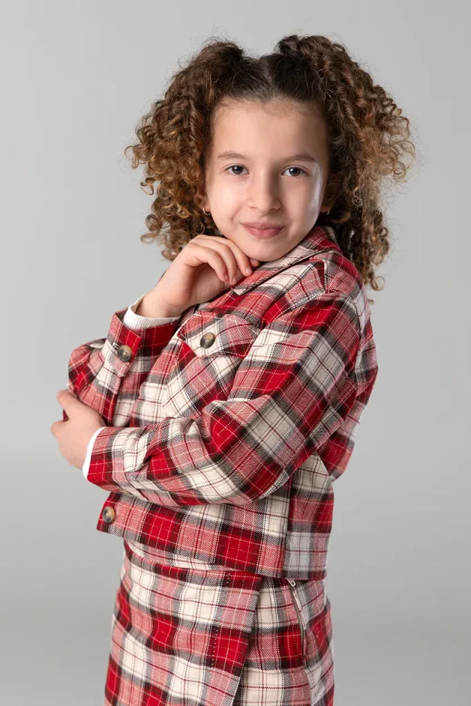 Natürliches Kinderportrait in Zofingen mit Mädchen im roten Karo-Outfit vor hellem Studiohintergrund