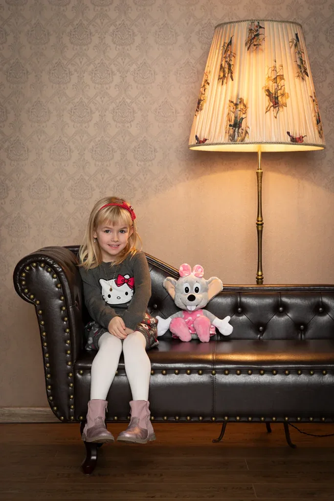 Liebevolles Kinderportrait in Zofingen mit Mädchen auf Sofa, warmem Licht und gemütlicher Studioatmosphäre