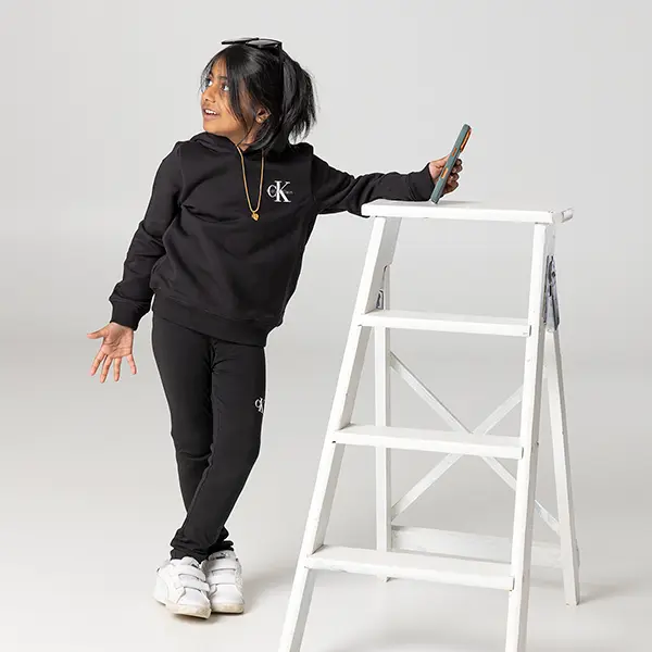 Mädchen steht spielerisch an einer weissen Leiter bei einem Kindershooting im Studio