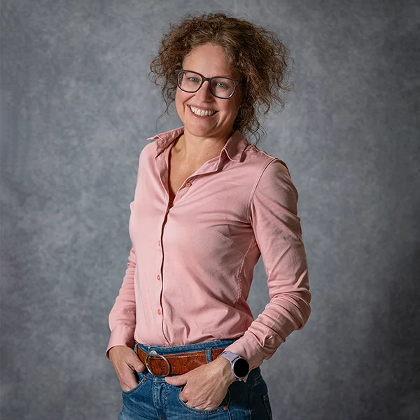Natürliches Businessportrait einer Frau mit Brille vor grauem Studiohintergrund