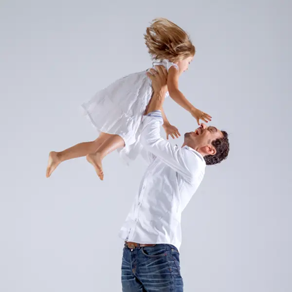 Vater hebt sein Kind lachend in die Luft bei einem natürlichen Familienfotoshooting