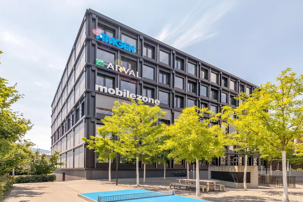 Aussenansicht eines mehrgeschossigen Bürogebäudes mit dunkler Fassade und Bäumen in Risch.