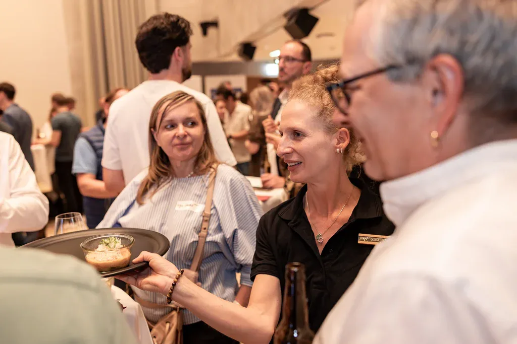 Service-Mitarbeiterin reicht einem Gast eine kleine Speise während eines Business-Events.