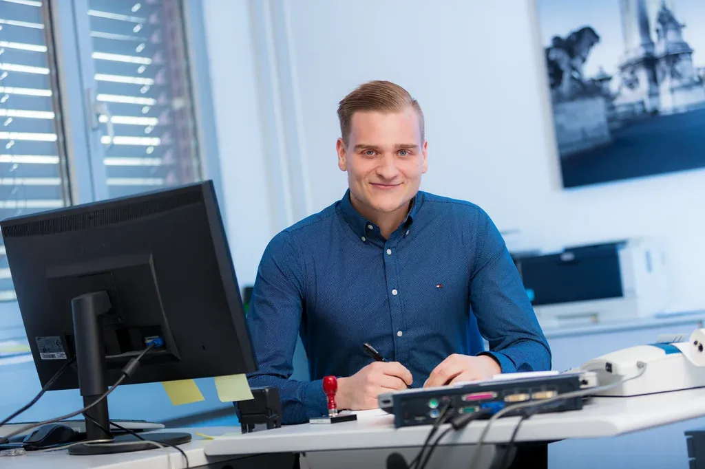 Businessportrait eines Mitarbeiters am Schreibtisch für Firmenprofil, Unternehmensfotografie und Online-Auftritt.