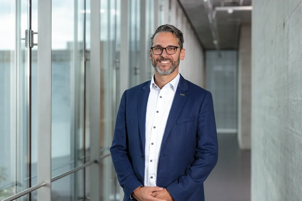 Businessportrait eines Mannes im Anzug in modernem Innenraum für Corporate Fotografie und Mitarbeiterportraits.