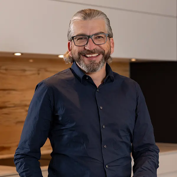 Lächelnder Küchenfachberater mit Brille in einem modern eingerichteten Küchenstudio.