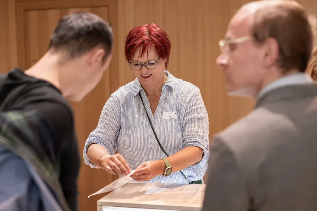 Mitarbeiterin verteilt Unterlagen am Check-in einer Firmenveranstaltung.