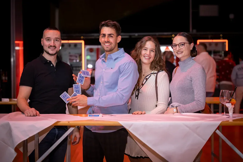 Vier Gäste erleben einen Kartentrick bei einer Close-up-Zaubershow am Firmenevent.