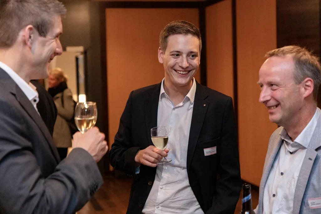 Drei Teilnehmer unterhalten sich entspannt mit Getränken bei einem Networking-Anlass in der Region Zofingen.