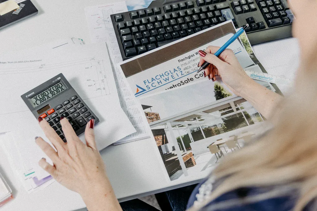 Hände arbeiten mit Taschenrechner und Stift an technischen Plänen eines Industriebetriebs in Wikon.