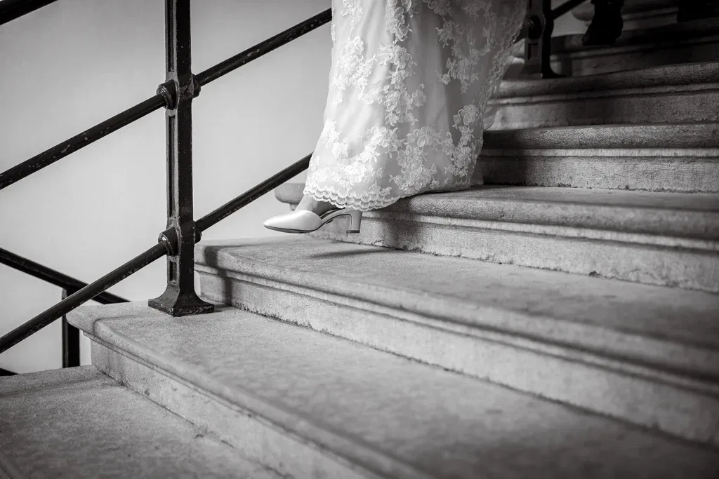 Detailaufnahme von Brautkleid und Brautschuhen auf einer Treppe in Schwarz-Weiss.