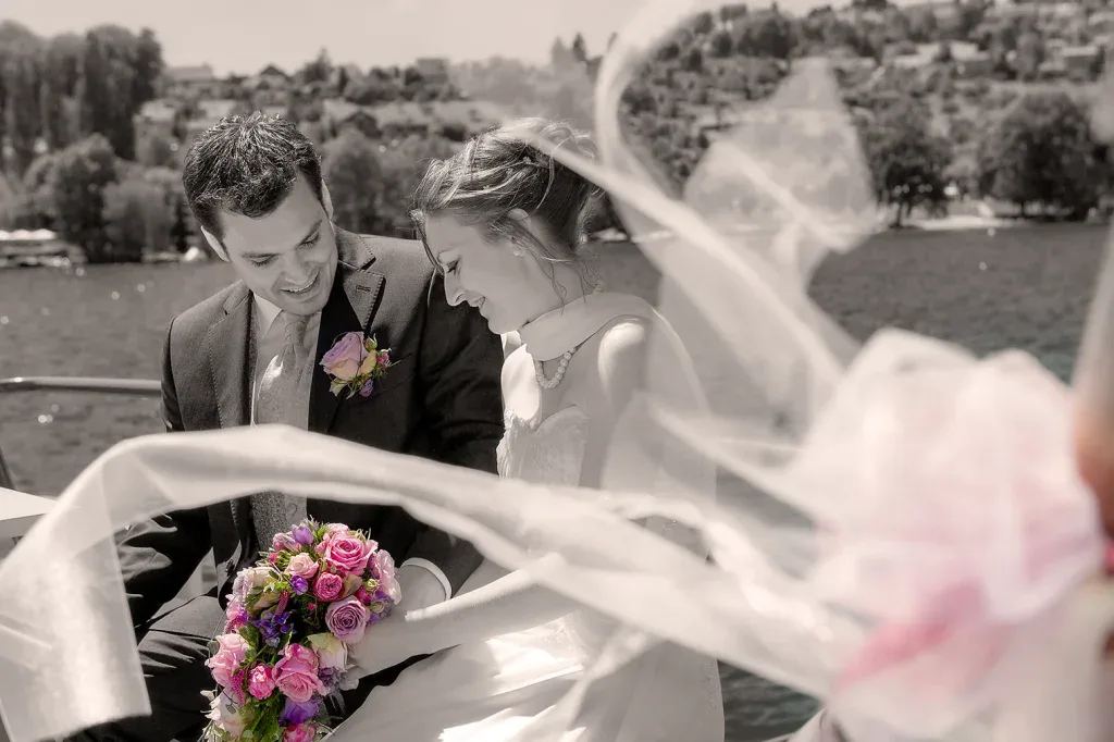 Brautpaar bei einem romantischen Hochzeitsportrait am See mit wehendem Schleier.