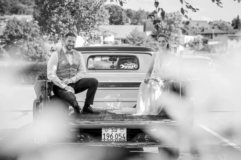 Brautpaar bei einem eleganten Hochzeitsportrait mit Oldtimer in Schwarz-Weiss.