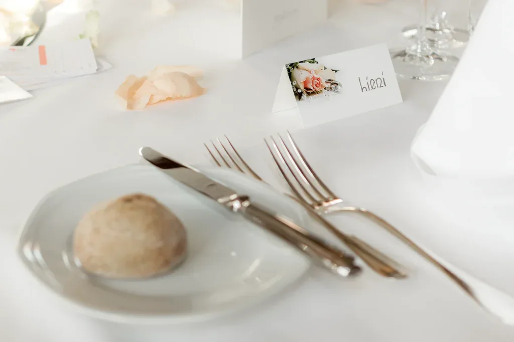 Detailaufnahme einer festlich gedeckten Hochzeitstafel mit Namenskarte und Ringen.