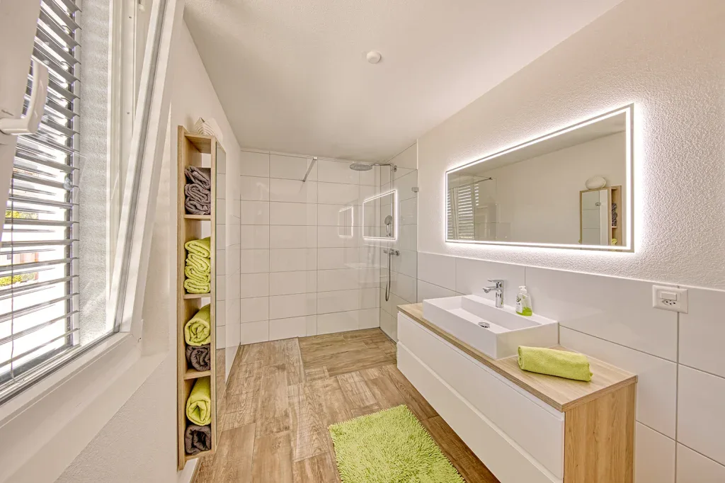 Helles Badezimmer mit grossem Spiegel, Doppelwaschtisch, Badewanne und klarer Innenarchitektur.