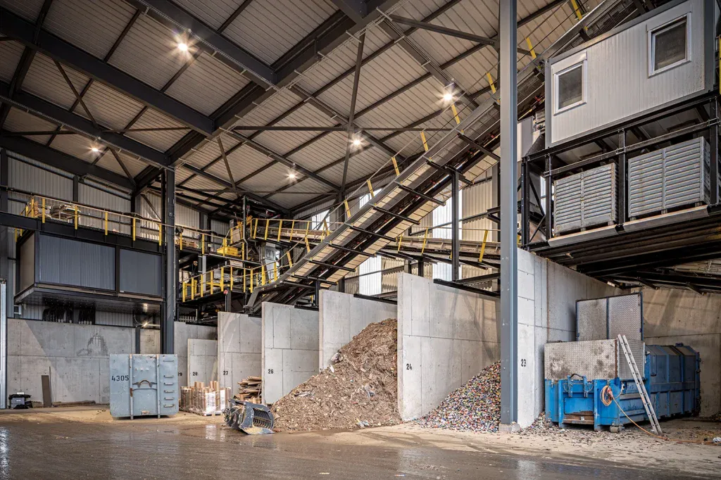 Grosszügige Industriehalle mit Förderanlagen, Materialboxen und verschiedenen Arbeitsbereichen.
