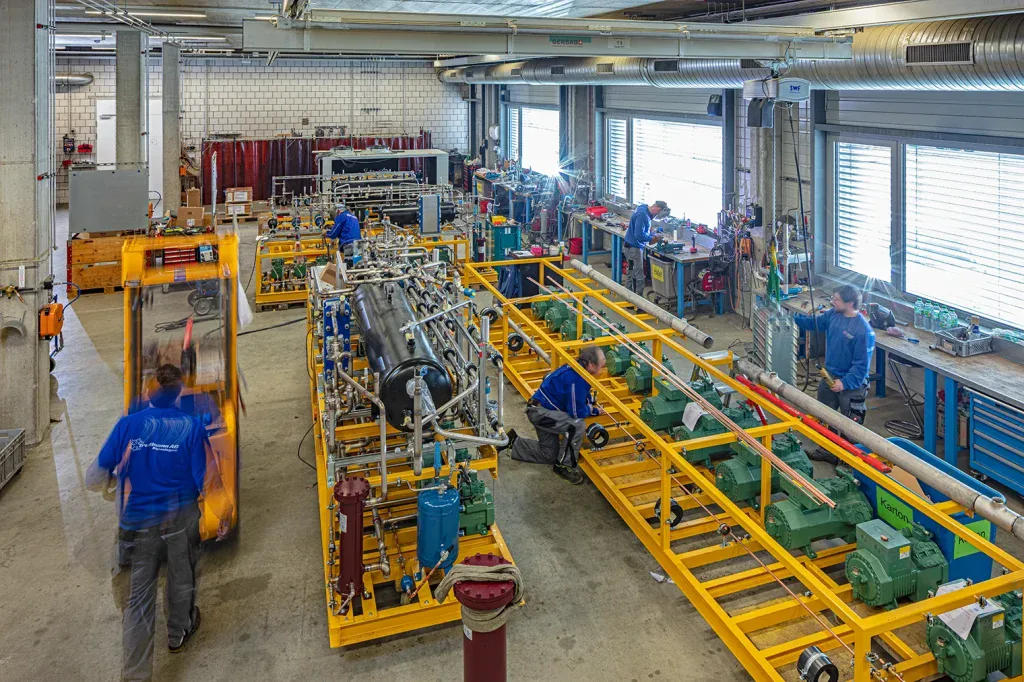 Überblick über eine industrielle Produktionshalle mit Maschinen, Fördertechnik und Mitarbeitenden.