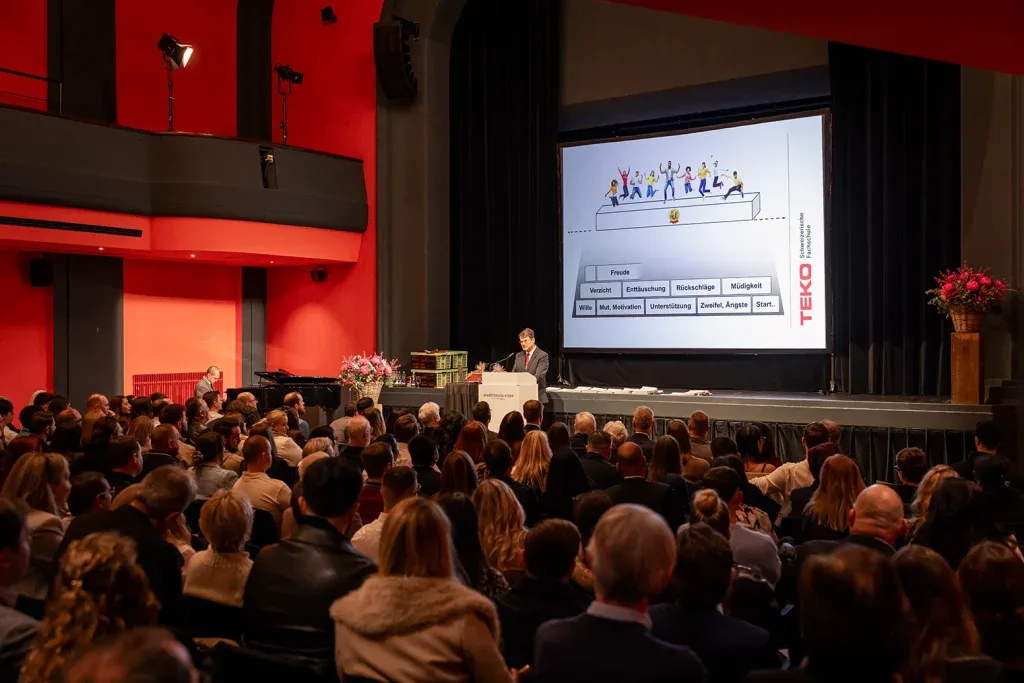 Referent spricht im Stadttheater Olten vor einem voll besetzten Saal.