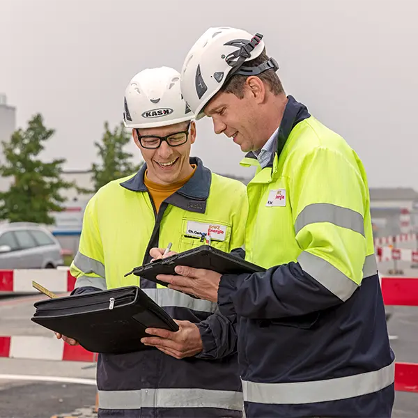 Zwei Mitarbeitende besprechen eine Baustelle anhand digitaler Pläne während einer Firmenreportage.
