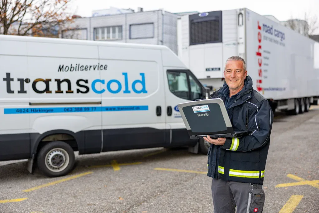 Servicetechniker präsentiert ein Diagnosegerät vor einem Servicefahrzeug für mobile Kühltechnik.