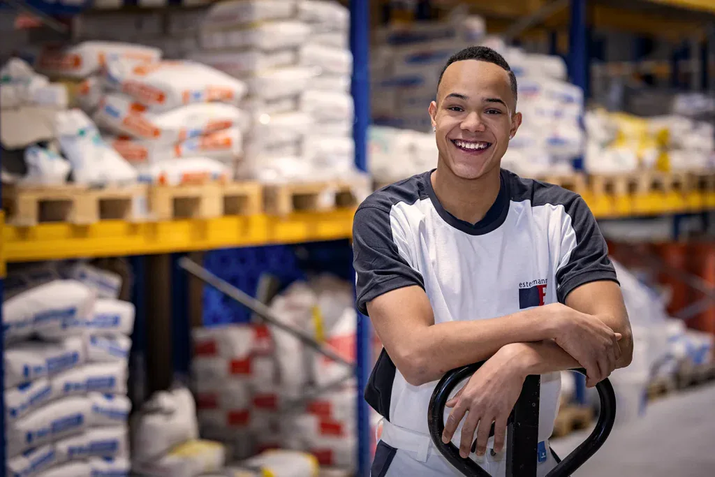 Sympathisches Mitarbeiterportrait eines jungen Mitarbeiters im Lager für Firmenreportage, Logistik und Employer Branding.