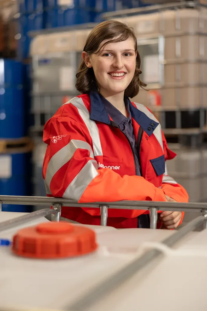 Mitarbeiterportrait einer Frau in Arbeitskleidung im Logistik- und Lagerumfeld für Unternehmenskommunikation.