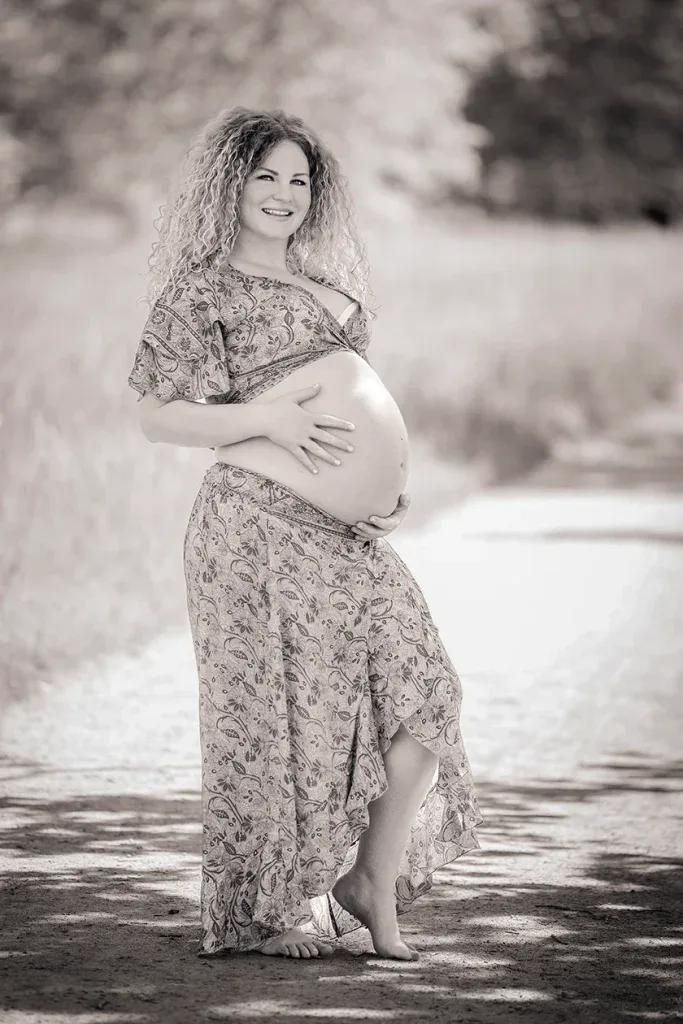 Schwangere Frau bei einem Outdoor-Babybauchshooting in Schwarz-Weiss mit natürlicher Lichtstimmung.
