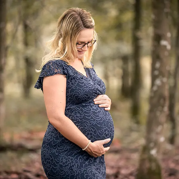 Schwangere Frau bei einem natürlichen Outdoor-Babybauchshooting im Wald.