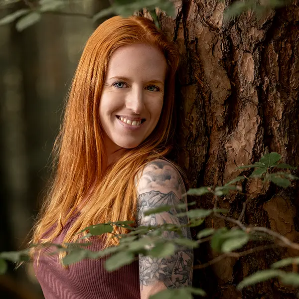 Natürliches Portrait einer Frau bei einem Outdoor-Fotoshooting im Wald bei Zofingen, angelehnt an einen Baum mit weichem Licht.