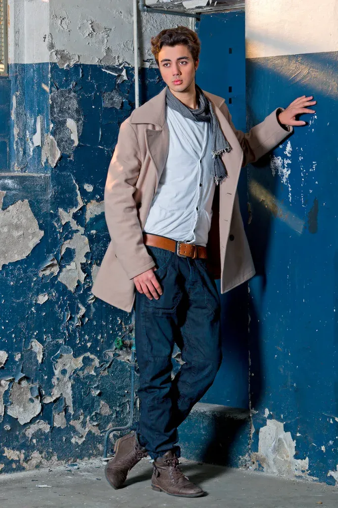 Junger Mann bei einem urbanen Portraitshooting an einer besonderen Location mit blauer Wand und natürlichem Ausdruck.