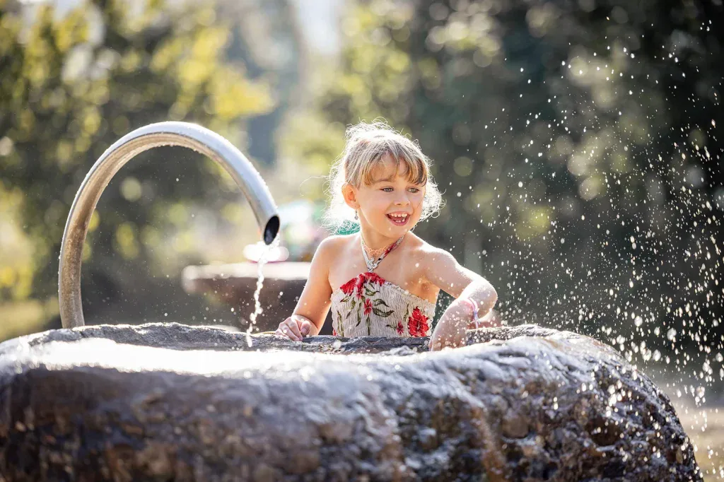 Kind bei einem lebendigen Outdoor-Fotoshooting mit Wasser und natürlichem Licht.