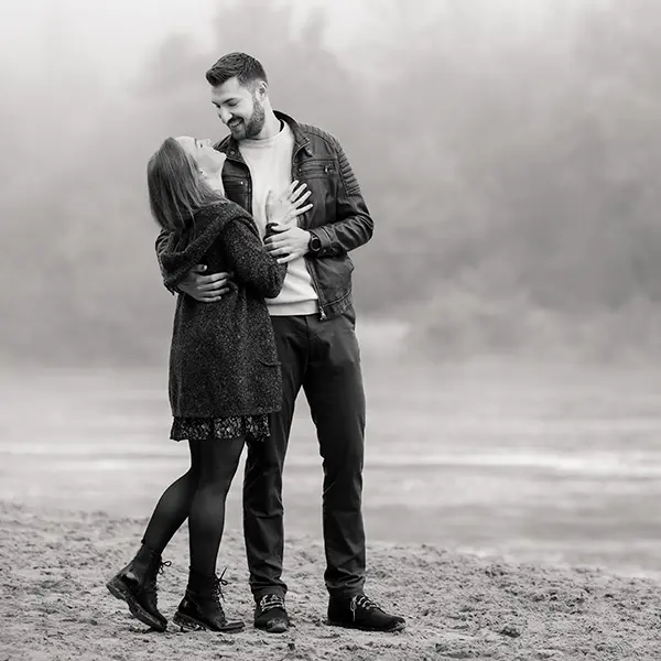 Paar bei einem emotionalen Outdoor-Fotoshooting in Schwarz-Weiss am Wasser.