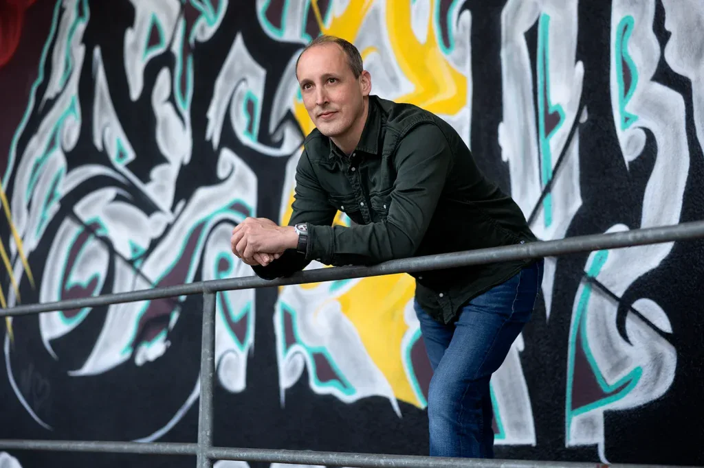 Mann bei einem Outdoor-Portraitshooting vor einer urbanen Graffiti-Wand in der Region Zofingen.
