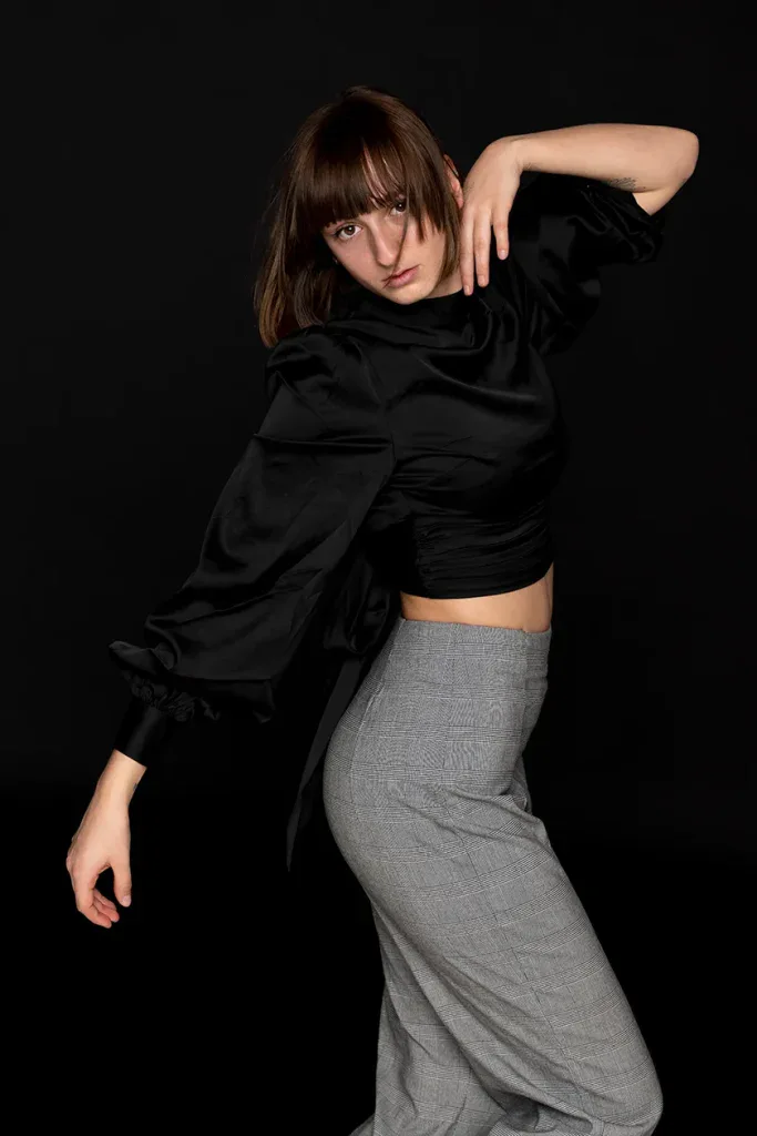 Ausdrucksstarkes Fashionportrait in Zofingen mit Frau in schwarzem Outfit vor dunklem Studiohintergrund.