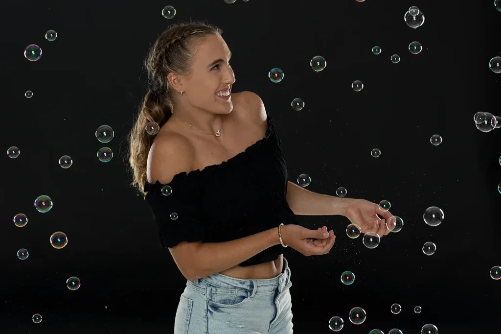 Verspieltes Portraitshooting in Zofingen mit Frau und Seifenblasen vor dunklem Studiohintergrund.
