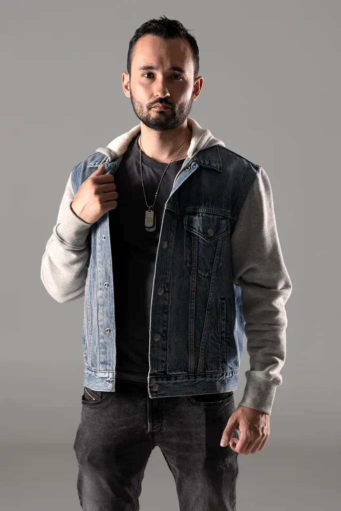 Modernes Portraitshooting in Zofingen mit Mann in Jeansjacke vor grauem Studiohintergrund.